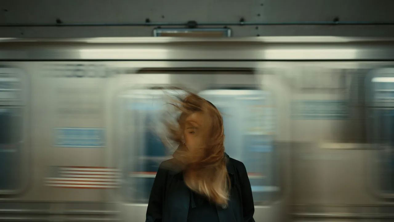 A person on a subway platform as a train streaks past in a long exposure.