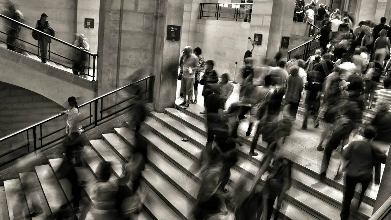 People blurred in motion on a wide stone staircase, in black and white.
